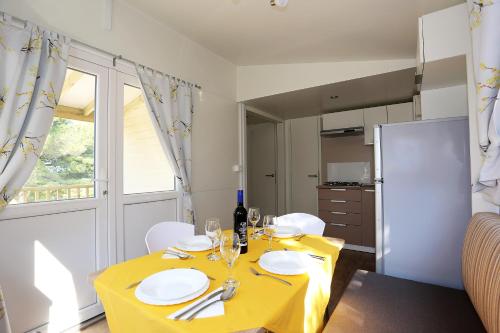a dining room with a yellow table with white plates at Mobile homes-Slanica in Murter