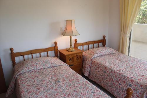 two beds in a bedroom with a lamp on a night stand at Galatia's Court in Paphos City