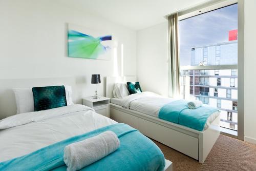 a bedroom with two beds and a large window at 2 Bedroom 2 Bathroom Apartment in Central Milton Keynes with Free Parking and Smart TV - Contractors, Relocation, Business Travellers in Milton Keynes