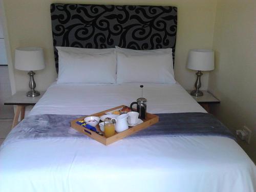 a tray with cups and mugs on a bed at Port House in Bloubergstrand