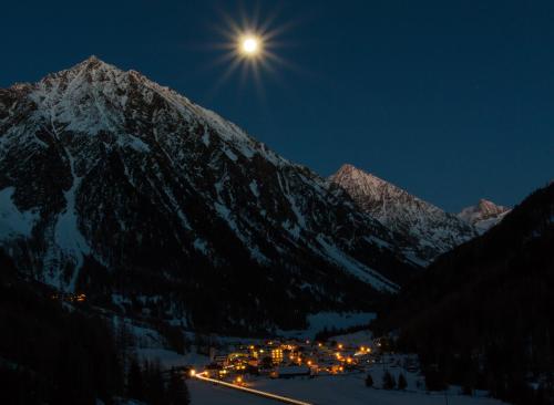 a full moon shines over a mountain village at night at Apart Silvana in Längenfeld