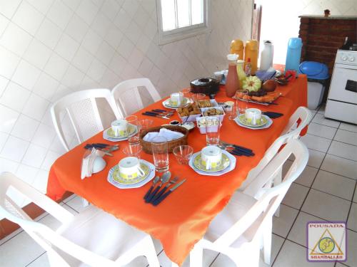 un tavolo da pranzo con tovaglia arancione e sedie bianche di Pousada Shamballah Paranapiacaba a Paranapiacaba