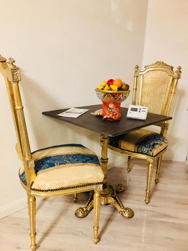 a table and two chairs with a bowl of fruit at Koetshuis Bosdam in Beveren
