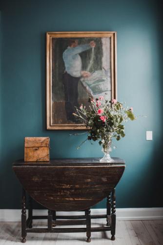 a vase of flowers on a table with a painting at Kjobing Manor in Ærøskøbing