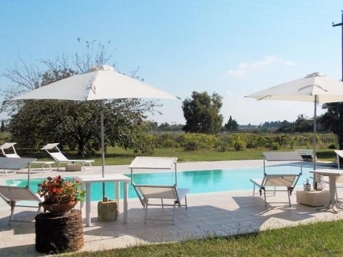 um grupo de cadeiras e mesas com guarda-sóis ao lado de uma piscina em B&B Villa I 2 Leoni em Lecce