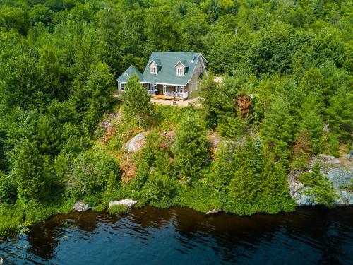 an aerial view of a house on a hill next to a river at Pourvoirie du Lac Blanc in Saint-Alexis-des-Monts
