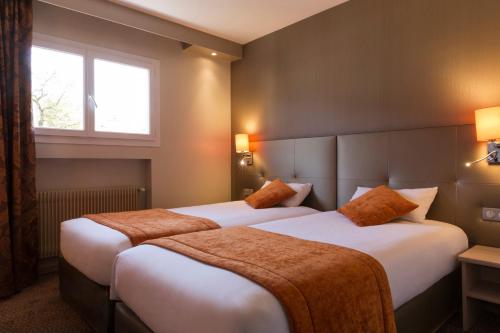 two beds in a hotel room with a window at The Originals City, Hôtel Rey du Mont Sion, Saint-Julien-en-Genevois Sud in Saint-Blaise