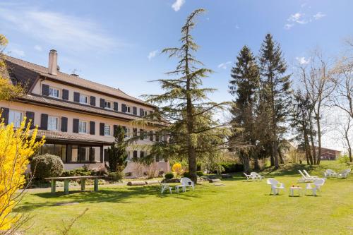 a large building with a yard with white chairs at The Originals City, Hôtel Rey du Mont Sion, Saint-Julien-en-Genevois Sud in Saint-Blaise