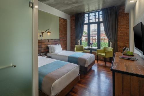 a hotel room with two beds and a television at Treasures Hotel and Suites in Malacca