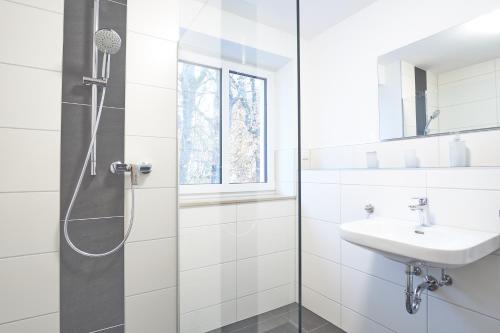 a white bathroom with a shower and a sink at Zur Friedenseiche in Aichach