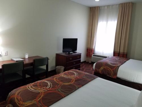 a hotel room with two beds and a desk and a television at Baymont by Wyndham Grovetown Augusta in Augusta