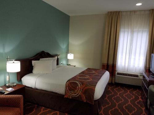 a hotel room with a large bed and a chair at Baymont by Wyndham Grovetown Augusta in Augusta
