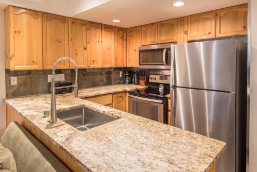 a kitchen with wooden cabinets and a stainless steel refrigerator at Valhalla Vacations at Whistler in Whistler