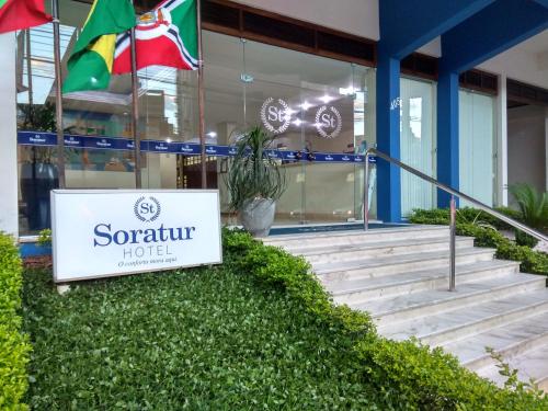 a sign in front of a building with a flag at Soratur Hotel & Coworking in Criciúma
