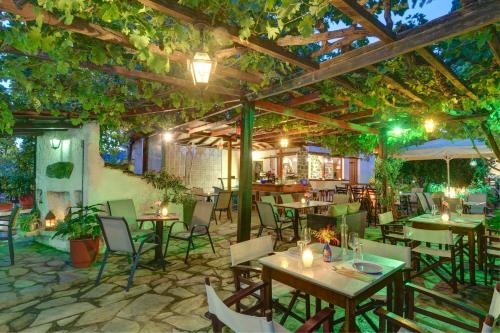 an outdoor restaurant with tables and chairs and trees at House Katia in Kalamos