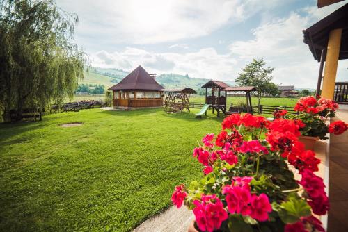 a garden with a gazebo and red flowers at Pension Elegance in Gura Humorului
