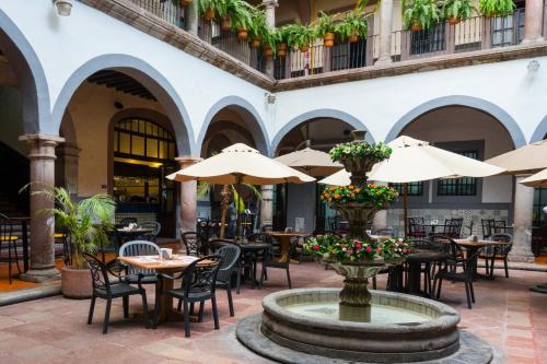 um pátio exterior com mesas, cadeiras e guarda-sóis em Hotel Hidalgo em Querétaro