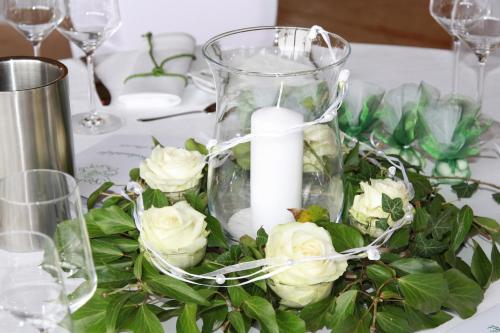 a centerpiece of white roses and a candle on a table at Gästehaus Landgut Lischow in Neuburg-Steinhausen