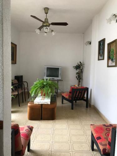 a living room with a ceiling fan and a tv at Las Violetas in San Clemente del Tuyú