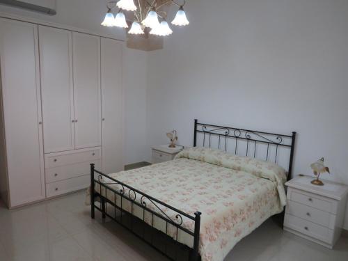 1 dormitorio con cama, armarios blancos y lámpara de araña en Casa Rita, en Manduria