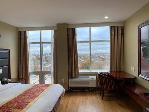 Habitación de hotel con cama, escritorio y ventanas grandes. en The Queens Hotel en Queens