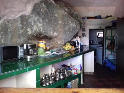 uma cozinha com um balcão verde e uma grande rocha em Caiat Lounge Refuge em Taghzoute