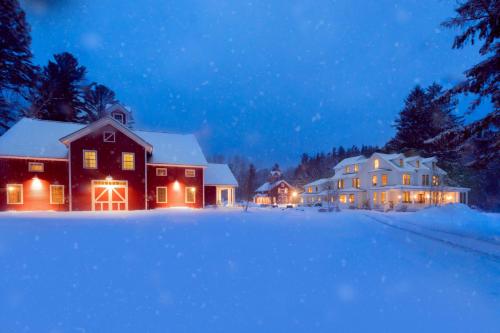 a house with lights on in the snow at night at The Inn at Manchester in Manchester