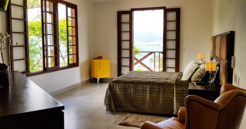 Un dormitorio con una cama y dos ventanas. en A Casa Bella - Guesthouse, en Ilhabela