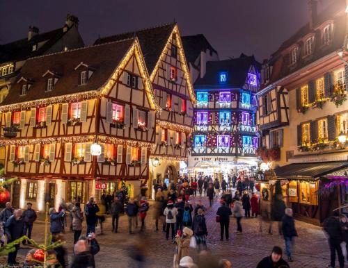 a group of people walking around a street with buildings at F1 Terrasse LED, Colmar à 5min, calme in Wintzenheim