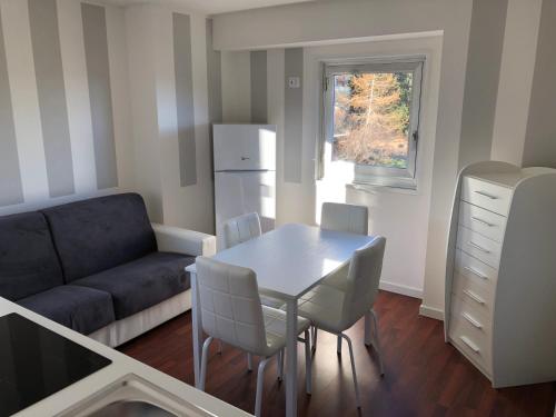 ein Wohnzimmer mit einem Tisch, Stühlen und einem Sofa in der Unterkunft Luna Bianca Apartment in Vermiglio