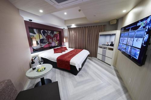 a hotel room with a bed and a flat screen tv at Hotel Sen (Adult Only) in Osaka