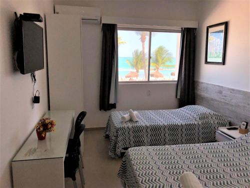 a hotel room with two beds and a window at Praia dos Carneiros apart beira-mar in Tamandaré