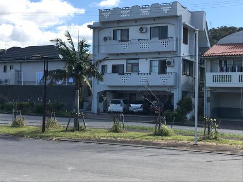 a white building with a palm tree in front of it at Takana in Nago
