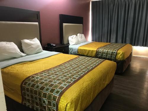 um quarto de hotel com duas camas com cobertores amarelos em Express Inn em Lafayette