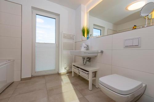 a white bathroom with a toilet and a sink at Annas Heimat am Meer in Olpenitz