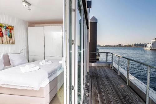 a bedroom with a bed on a balcony next to the water at Schwimmendes Haus Seebär in Olpenitz