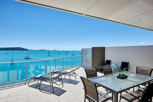 a balcony with tables and chairs and a view of the water at at Marina Shores in Airlie Beach