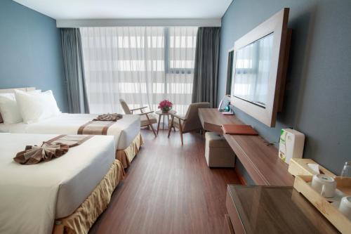 a hotel room with two beds and a tv at Libra Hotel Nha Trang in Nha Trang
