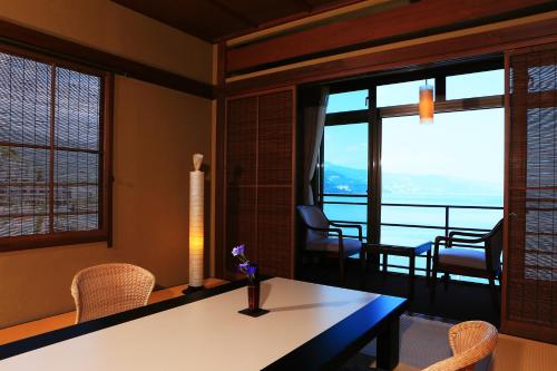 salon ze stołem, krzesłami i oknami w obiekcie Taiseikan w mieście Atami