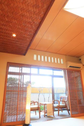 a room with a table and chairs and a large window at Taiseikan in Atami