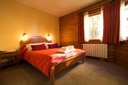 a bedroom with a bed with red sheets and a window at Linda Vista Apart Hotel in El Calafate