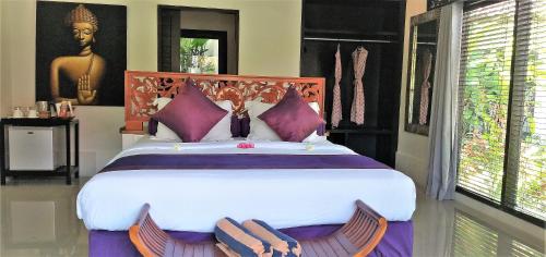 a bedroom with a large bed with two chairs at Katala Suites and Villas in Sanur