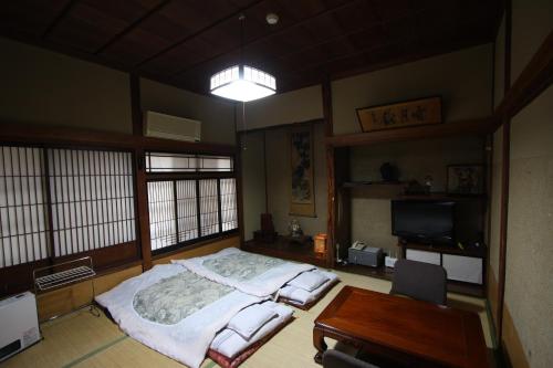 a bedroom with a bed and a desk and a table at Yamadaya Ryokan in Nozawa Onsen