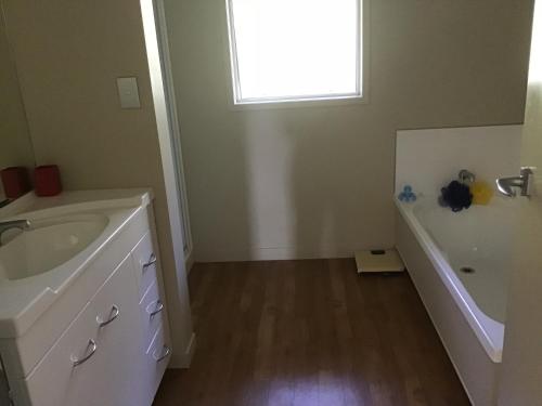 a bathroom with a sink and a tub and a window at Treetops On Heta in New Plymouth