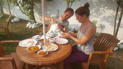 Un hombre y una mujer sentados en una mesa con comida. en One More Day Hostel, en Weligama