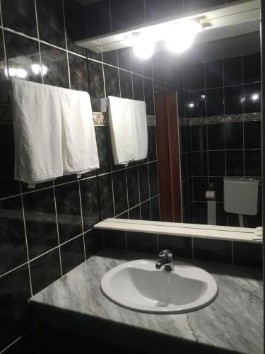a bathroom with a sink and a mirror and towels at Vila Romanitza in Dărmăneşti