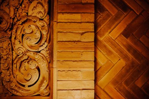 a wooden door with a carving on a wall at Phor Liang Meun Terracotta Arts in Chiang Mai