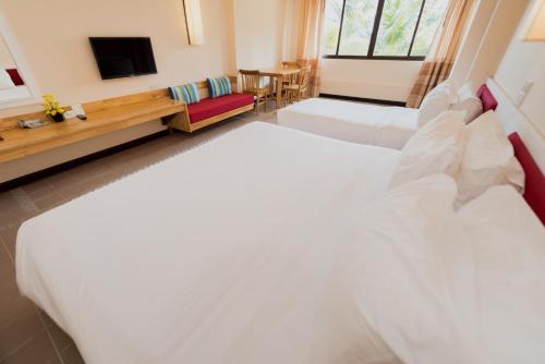 a hotel room with two beds and a television at Rayong Resort Hotel in Ban Phe