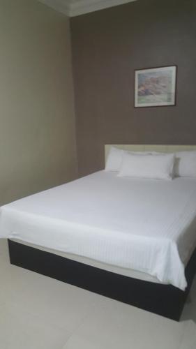 a bed with white sheets and pillows in a bedroom at HOTEL SHAFURA 1 in Cukai