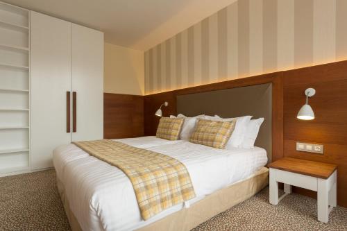 a bedroom with a large white bed and a table at Ruskovets Thermal SPA & Ski Resort in Bansko
